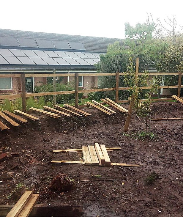 Fencing is installed on a bank adjacent to the medical centre, providing screening and security.
