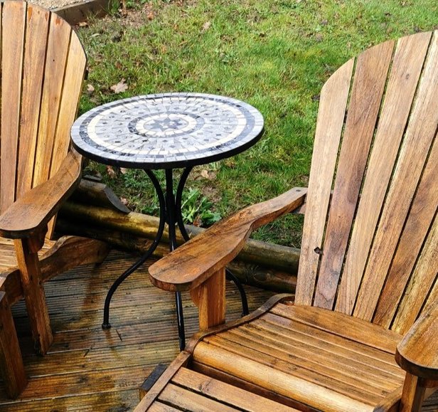 Two wooden garden recliners and a round coffee table that have been cleaned to restored the wood colour and remove the dirt.